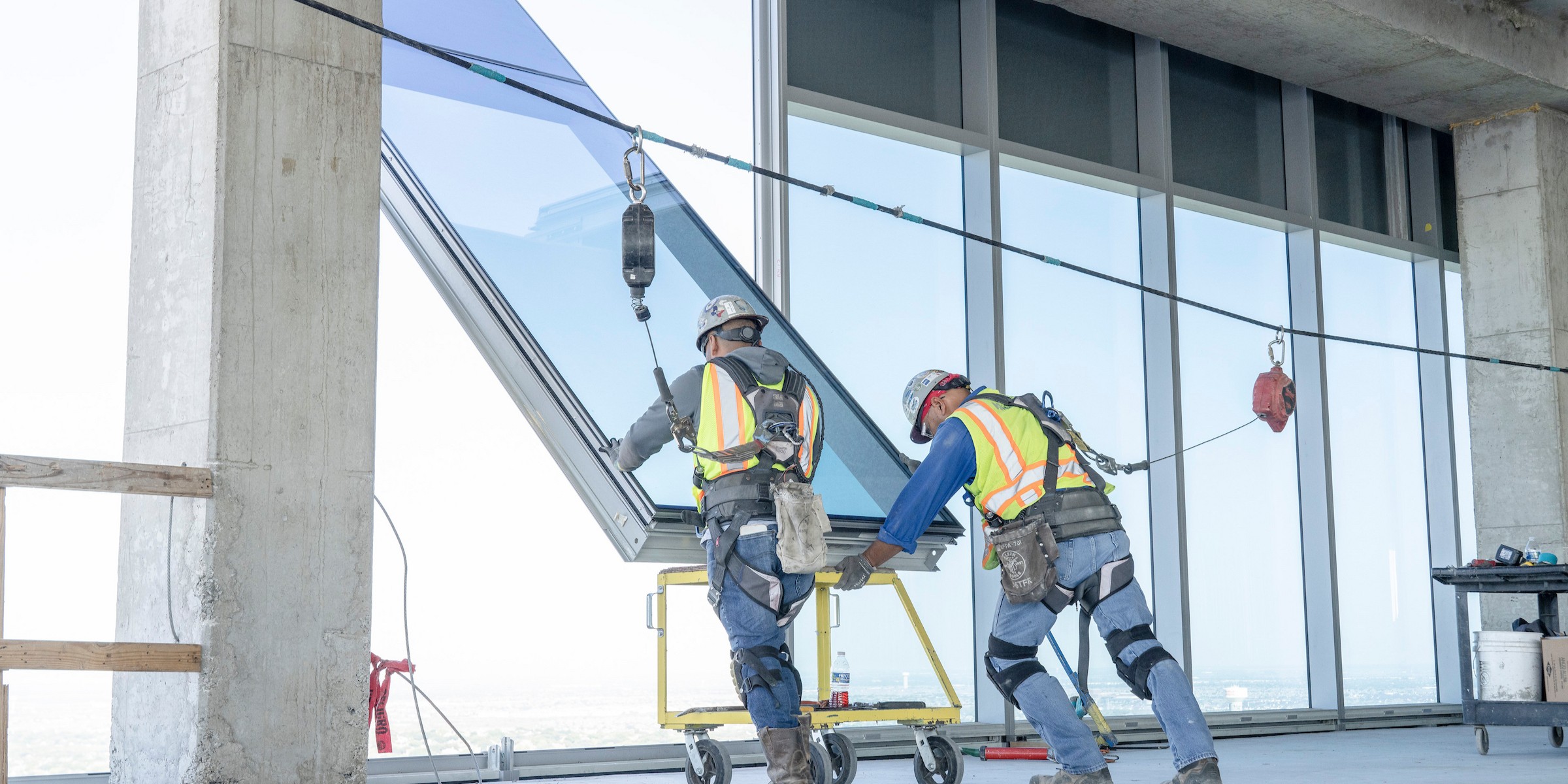 glaziers setting a large glass panel into curtain wall
