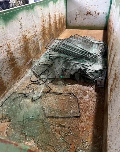 glass being dumped into the dumpster for recycling