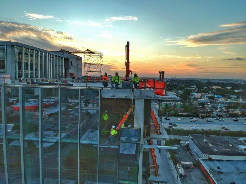 Glaziers and crane lift heavy unit to top of building 