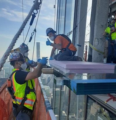 four glaziers work together on the exterior of a building