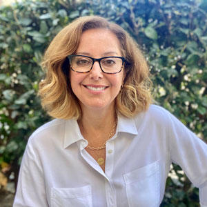 woman with curly brown hair wearing glasses and smiling
